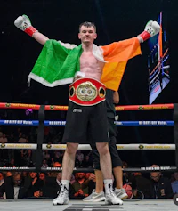 a boxer is holding up an irish flag in the ring